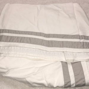 White crib skirt with gray stripes.